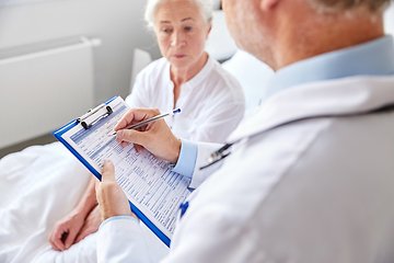 Image showing senior woman and doctor with clipboard at hospital