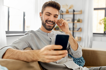 Image showing man in earphones listening to music on smartphone