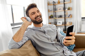 Image showing man in headphones listening to music on smartphone