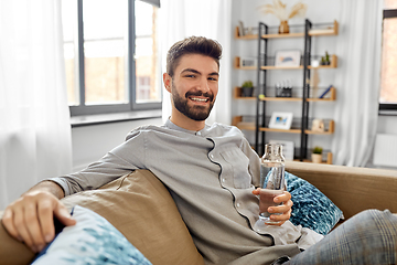 Image showing happy man drinking water from glass bottle at home