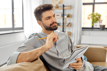 Image showing man writing to notebook and thinking at home