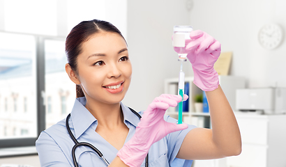 Image showing happy asian female nurse with medicine and syringe