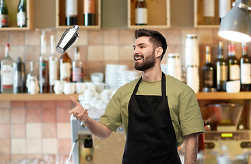 Image showing happy barman with shaker preparing drink at bar