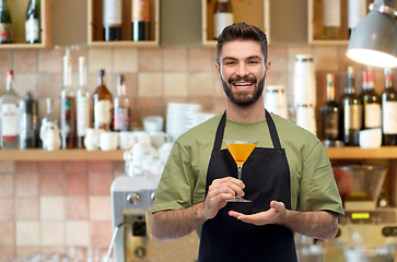 Image showing barman in apron with glass of cocktail at bar