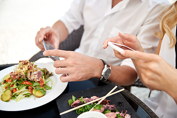 Image showing couple with smatphones photographing food