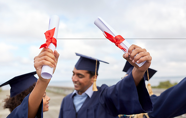 Image showing graduate students in mortar boards with diplomas