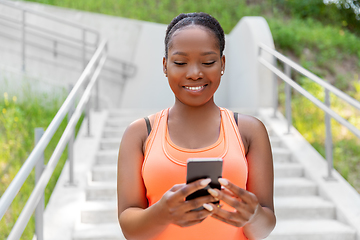 Image showing smiling sporty african woman using smartphone