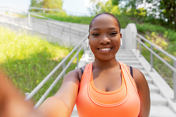 Image showing happy african woman with earphones taking selfie