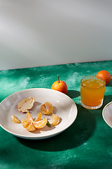 Image showing peeled mandarins on plate and glass of juice