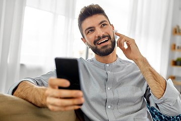 Image showing man in earphones listening to music on smartphone