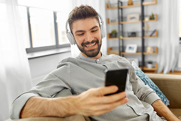 Image showing man in headphones listening to music on smartphone