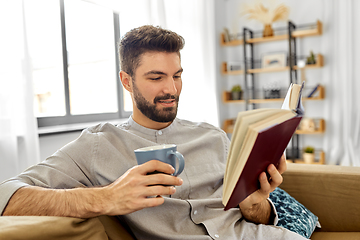 Image showing man reading book and drinking coffee at home