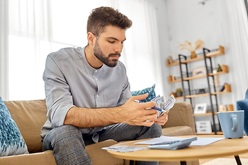 Image showing man with money and calculator filling papers