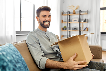 Image showing happy smiling man opening parcel box at home