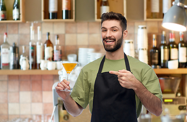 Image showing barman in apron with glass of cocktail at bar