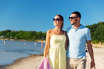 Image showing happy couple with picnic basket walking on beach