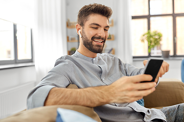 Image showing man in earphones listening to music on smartphone