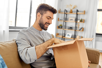 Image showing happy smiling man opening parcel box at home