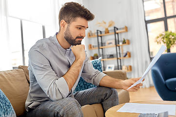 Image showing stressed man with bills at home