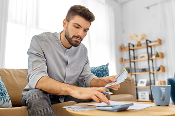 Image showing man with money and calculator filling papers