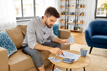 Image showing man with money and calculator filling papers