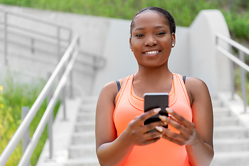 Image showing smiling sporty african woman using smartphone