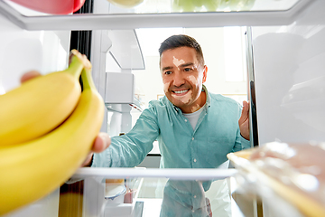 Image showing man with vitiligo taking banana from fridge