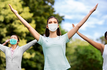 Image showing group of women in masks doing yoga at summer park