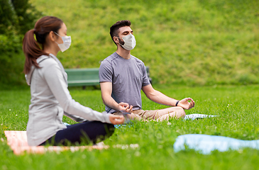 Image showing people in masks meditating at summer park