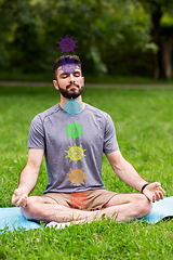 Image showing young man meditating at park with seven chakras