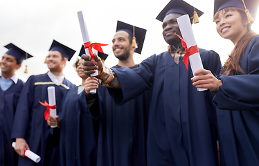 Image showing graduate students in mortar boards with diplomas