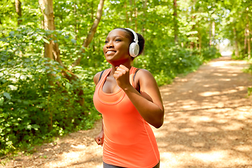 Image showing happy african woman in headphones running in park