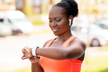 Image showing happy african woman with earphones and smart watch