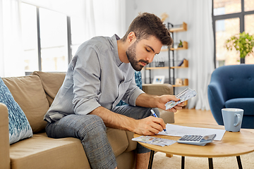 Image showing man with money and calculator filling papers