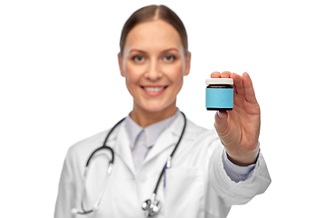 Image showing smiling female doctor holding jar of medicine