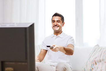 Image showing smiling middle aged man with vitiligo watching tv