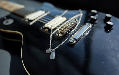 Image showing close up of bass guitar with metallic pendant