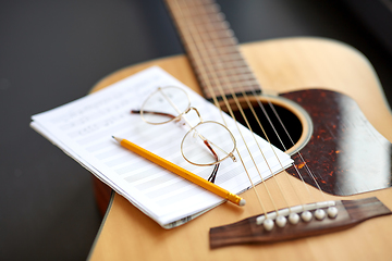 Image showing close up of guitar, music book, pencil and glasses