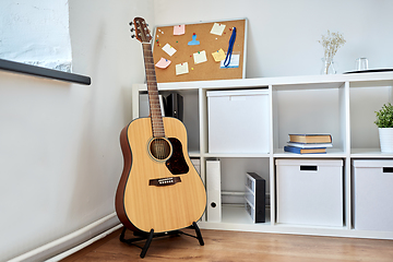 Image showing close up of acoustic guitar on stand at home