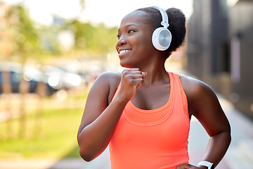 Image showing happy african woman in headphones running outdoors