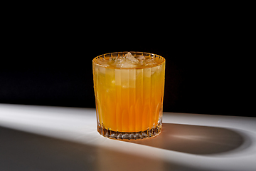 Image showing glass of orange juice with ice on table