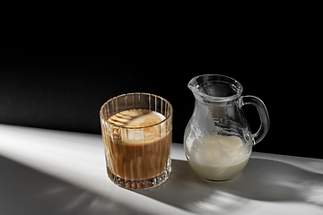 Image showing coffee in glass and jug of milk or cream on table