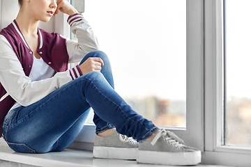 Image showing sad teenage girl sitting on window sill