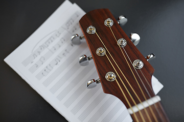 Image showing close up of acoustic guitar head with music book