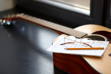 Image showing close up of guitar, music book, pencil and glasses