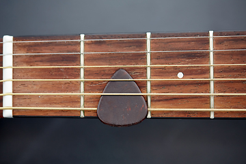 Image showing close up of guitar neck with pick between strings