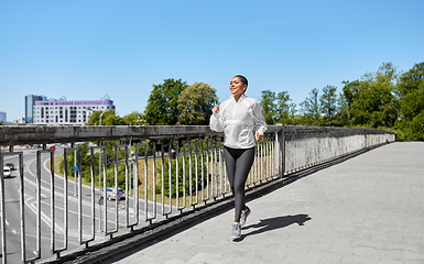 Image showing african american woman running along bridge