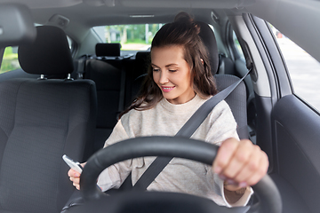 Image showing smiling woman or female driver driving car in city