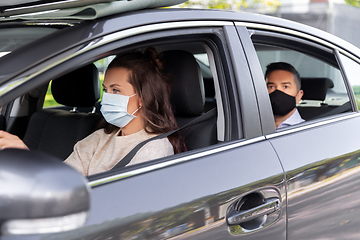 Image showing female driver in mask driving car with passenger