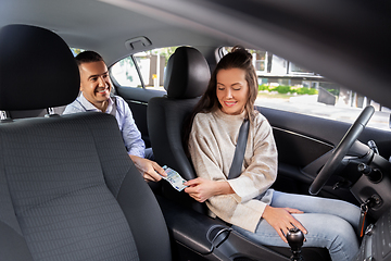 Image showing female car driver taking money from passenger